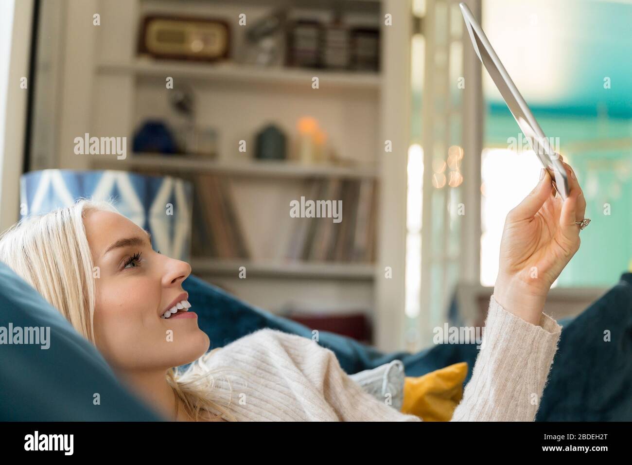 Woman using tablet while lying on sofa Stock Photo