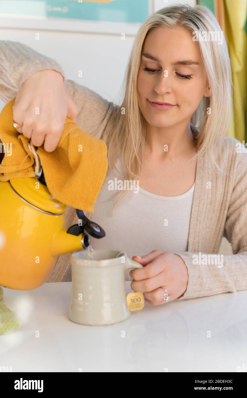 Woman making tea, pouring water from kettle Stock Photo Alamy
