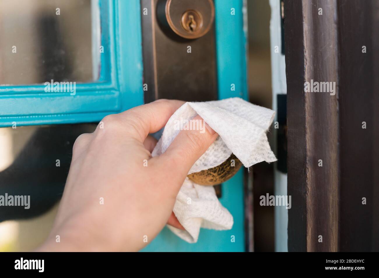 Close-upÂ of hand wiping down knob with disinfectant Stock Photo