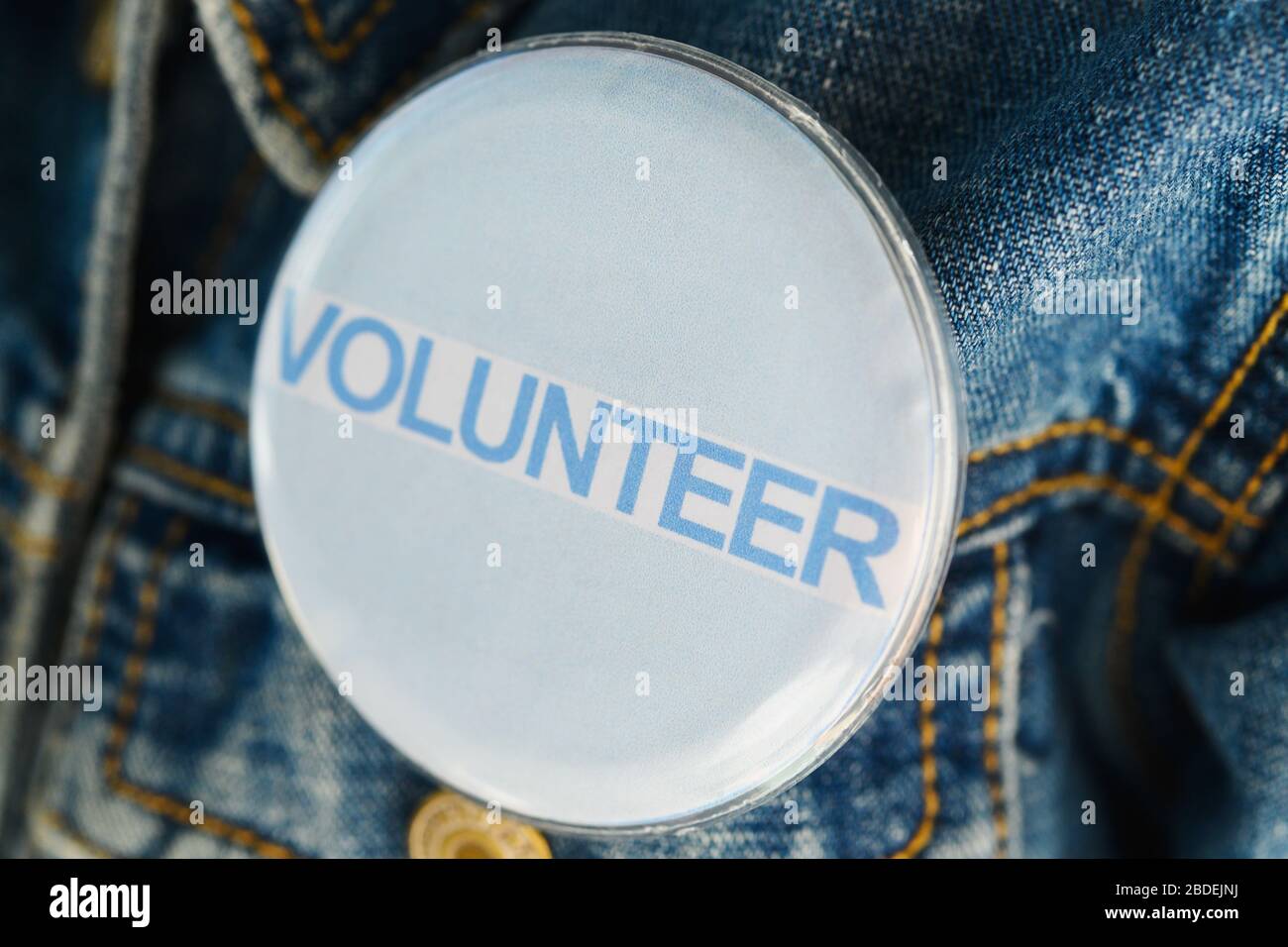 Close up of Volunteer button on denim jacket Stock Photo