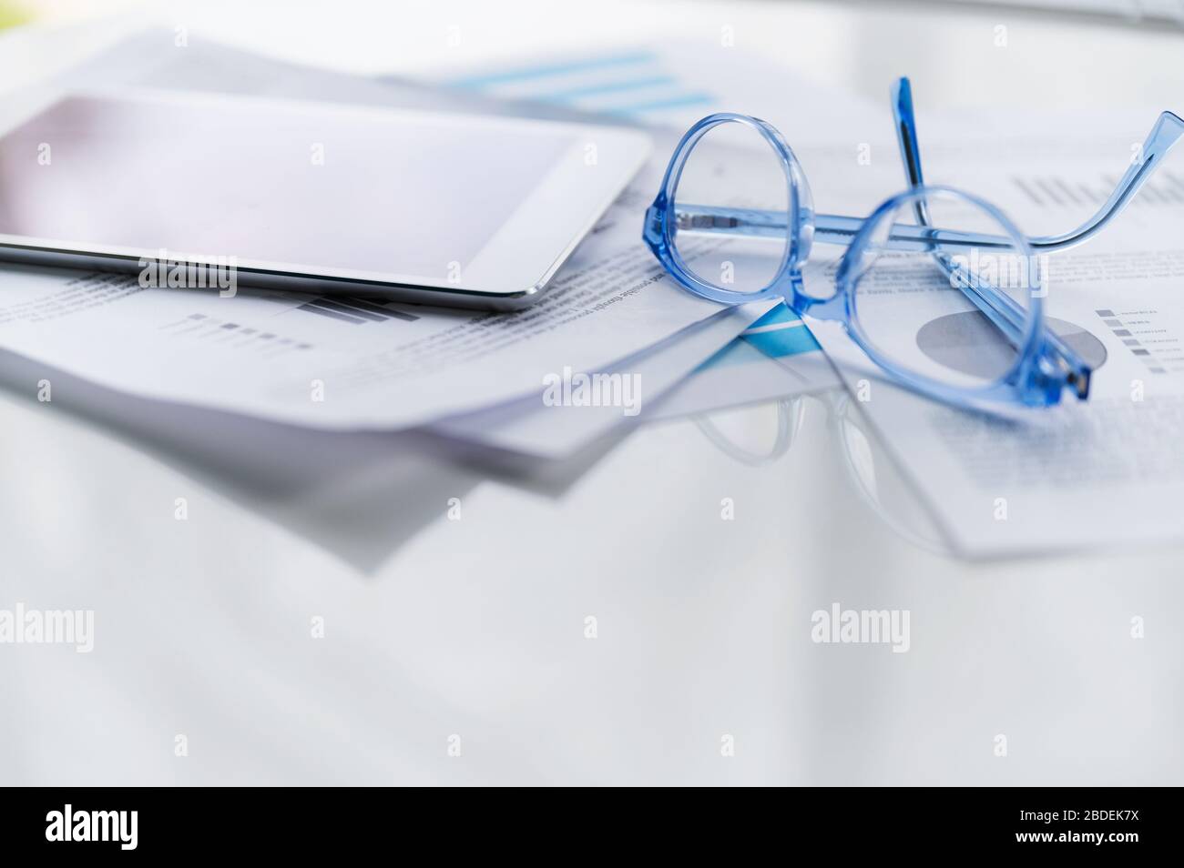 Blue eyeglasses and tablet on business papers Stock Photo