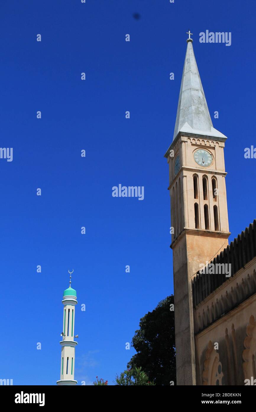 Anglican Cathedral spire with a Mosque minaret in the background, Stone Town, Zanzibar Stock Photo