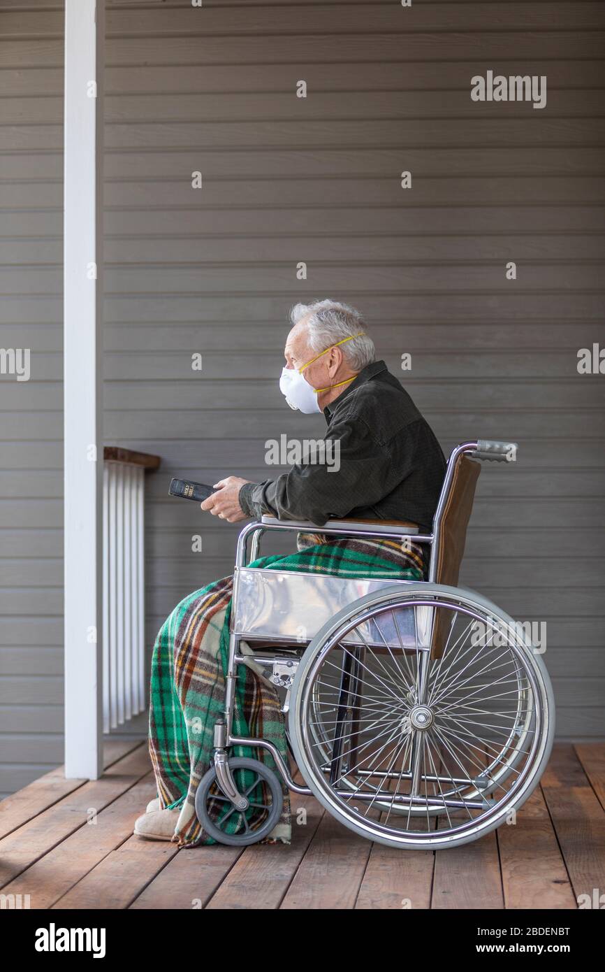 Senior man in wheelchair wearing protective mask to preventÂ coronavirusÂ transmission on porch Stock Photo