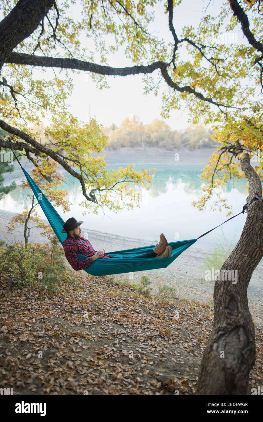 Italy, Man lying in hammock near lake Stock Photo