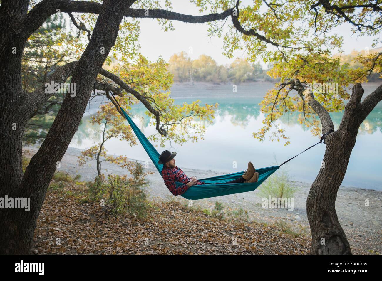 Italy, Man lying in hammock near lake Stock Photo