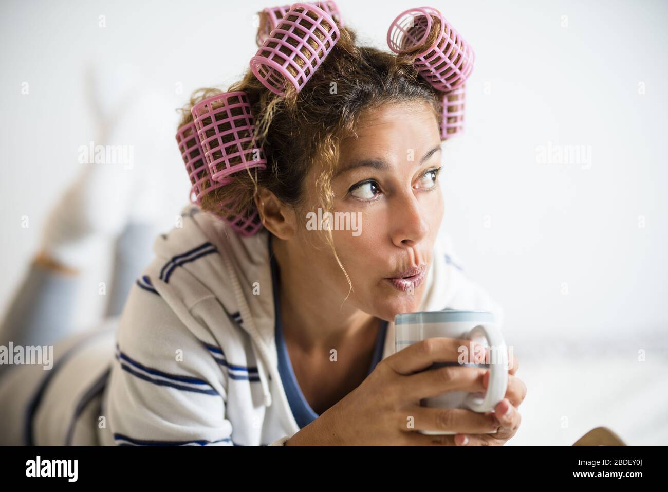 Woman with hair curlers holding mug Stock Photo