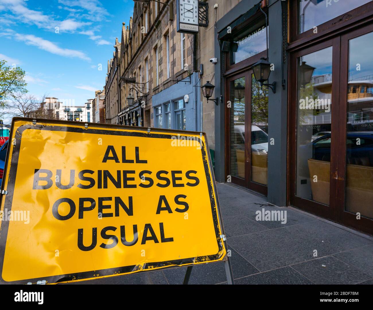 Leith, Edinburgh, Scotland, UK. 8th Apr, 2020. Covid-19 lockdown: A 'Businesses Open as Usual' sign placed during the Trams to Newhaven roadworks is now out of place as all the normally busy restaurants and bars on The Shore are closed down due to the pandemic Stock Photo