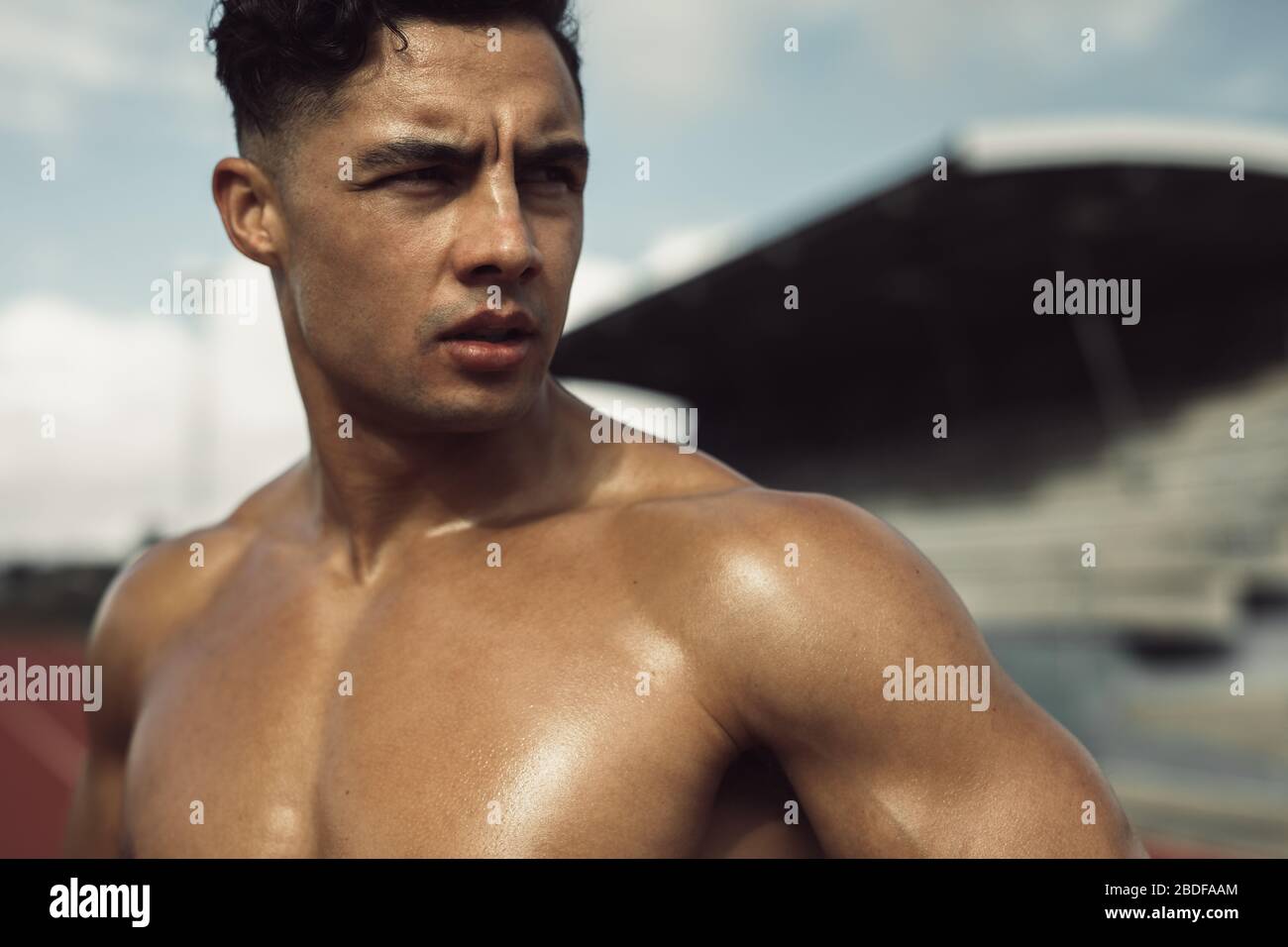 Fit and strong man relaxing after exercise. Muscular male runner taking a break after a run on
