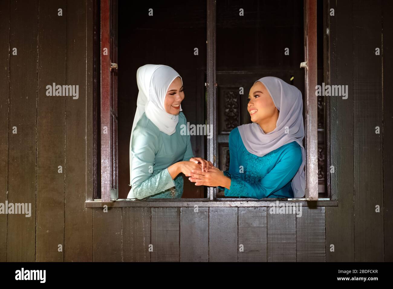 Muslim Malay women wearing hijab and traditional costume shaking hand ...