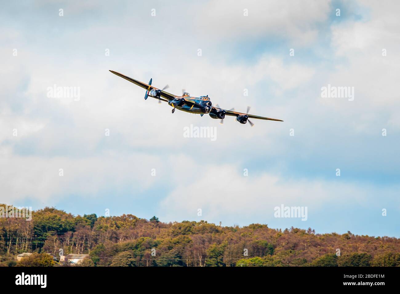 Lancaster Bomber banking low pass over fields and trees whilst taking part in celebrations for Leeds Bradford Airport's 90th birthday on 20.10.2011 Stock Photo