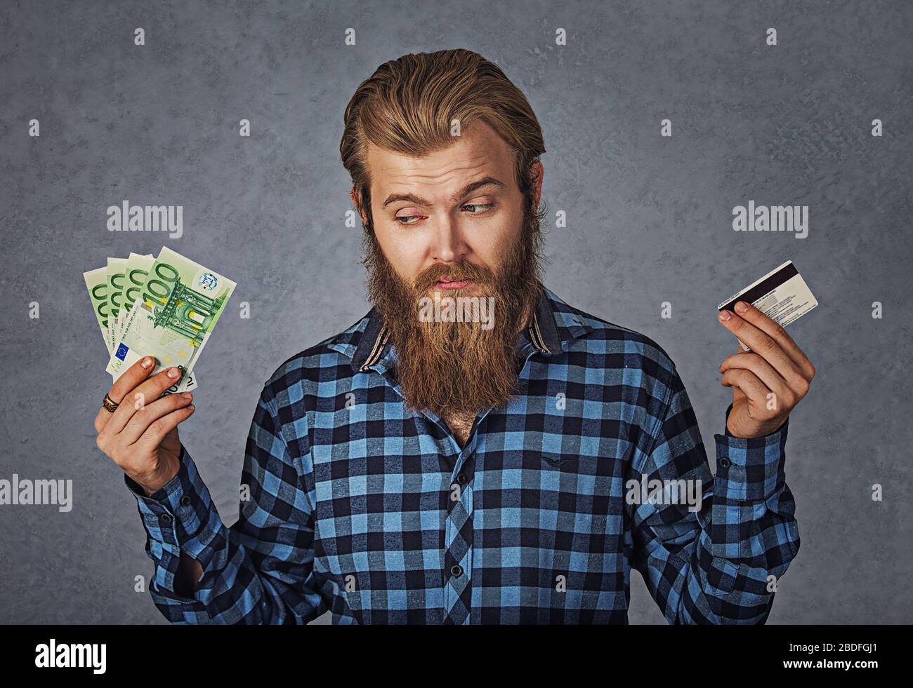 Businessman choosing holding showing plastic credit card or money cash euro banknotes bills, grey background Stock Photo