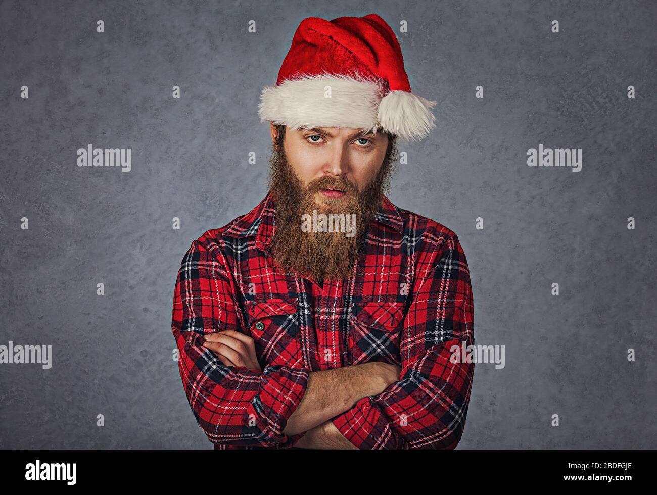 Skeptical tired bearded man in santa claus hat isolated grey gray background. Stock Photo