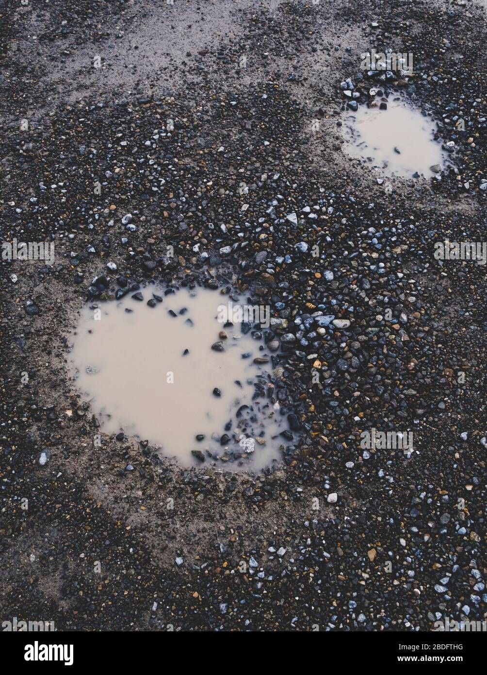 Two potholes on wet gravel road Stock Photo Alamy