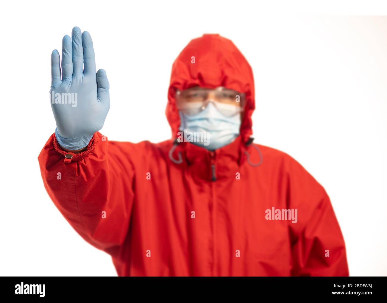 Person with mask and hand raised in red protective suit, stop concept for social distancing Stock Photo