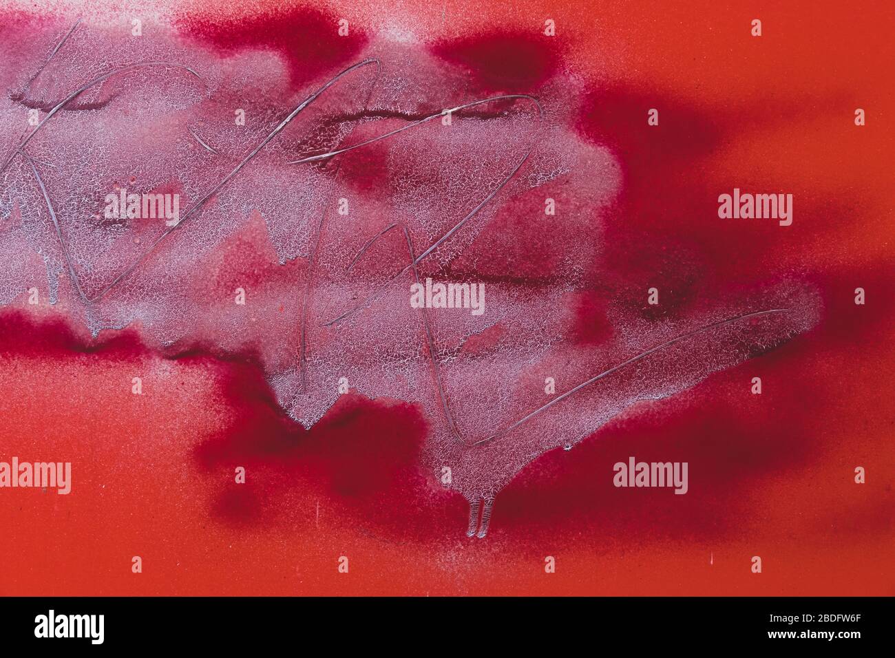 Bright red graffiti paint and scratch marks on urban wall Stock Photo