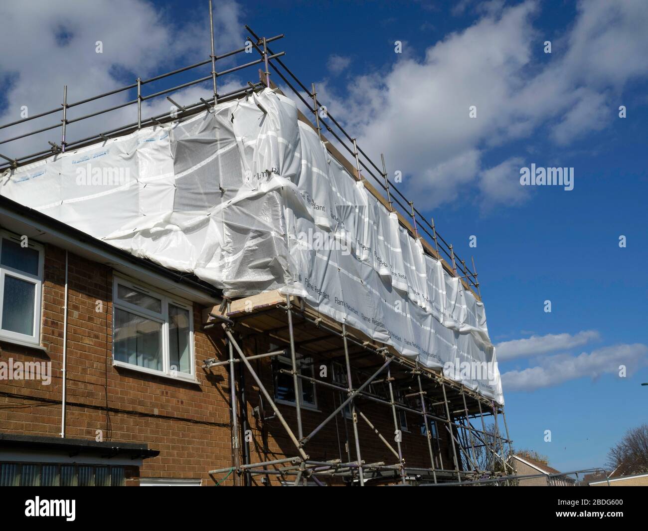 Scaffolding covered with flame retardant sheeting for weather protection of a house whose upper storey and roof had been destroyed by fire Stock Photo