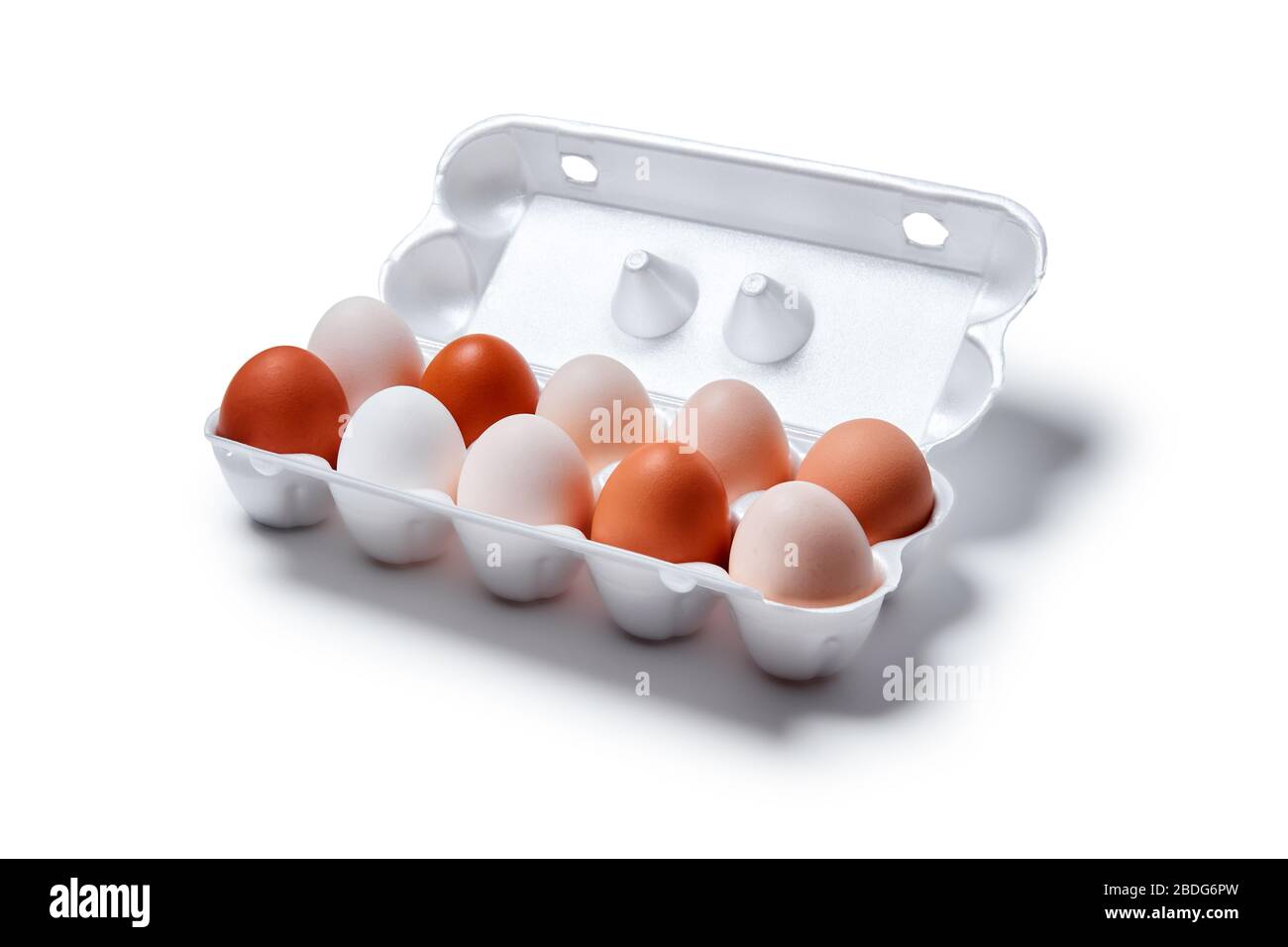 eggs of different shades from white to brown are packed together in one egg crate, isolated on a white background Stock Photo