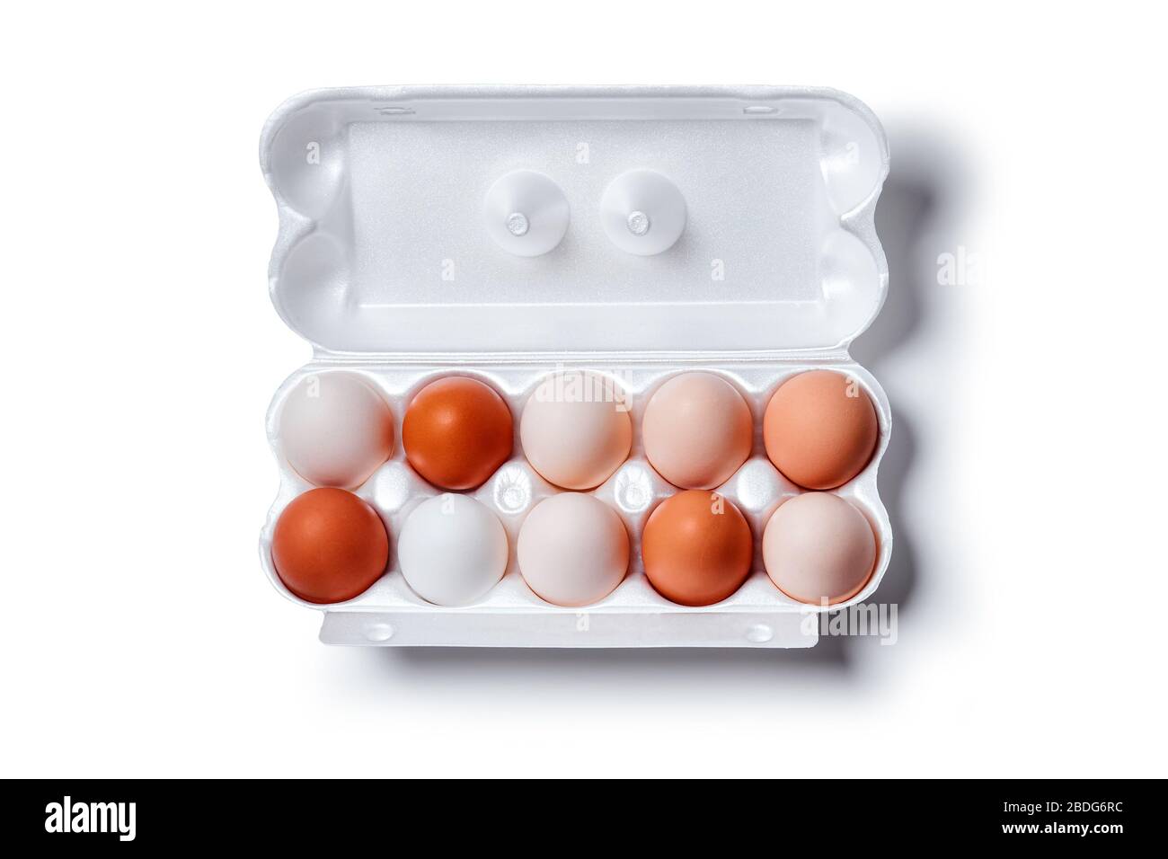 eggs of different shades from white to brown are packed together in one egg crate, isolated on a white background, horizontal top view, Stock Photo