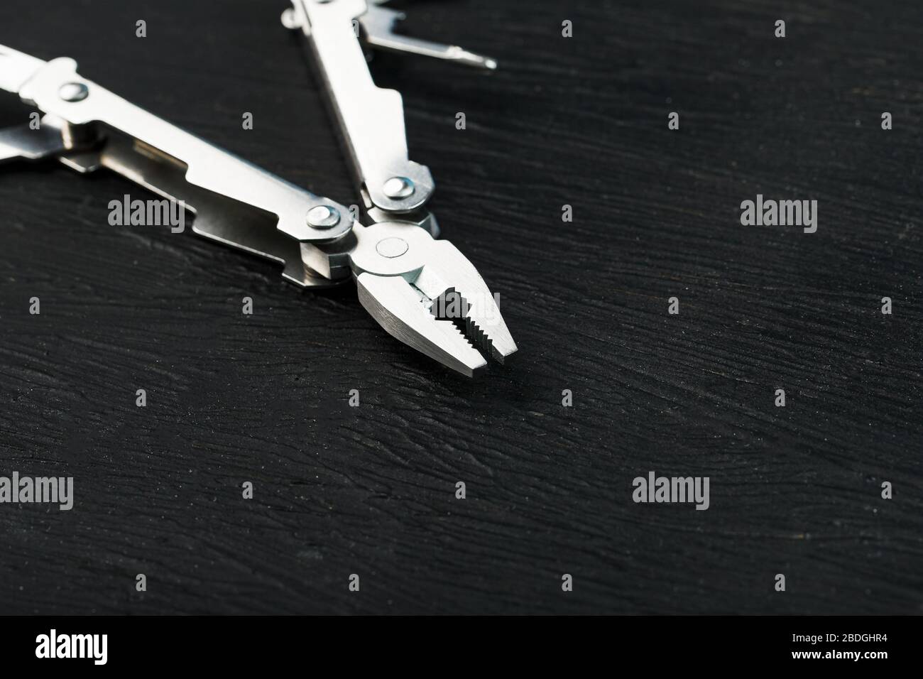 Multi-functional tool on a black textural background. Stock Photo