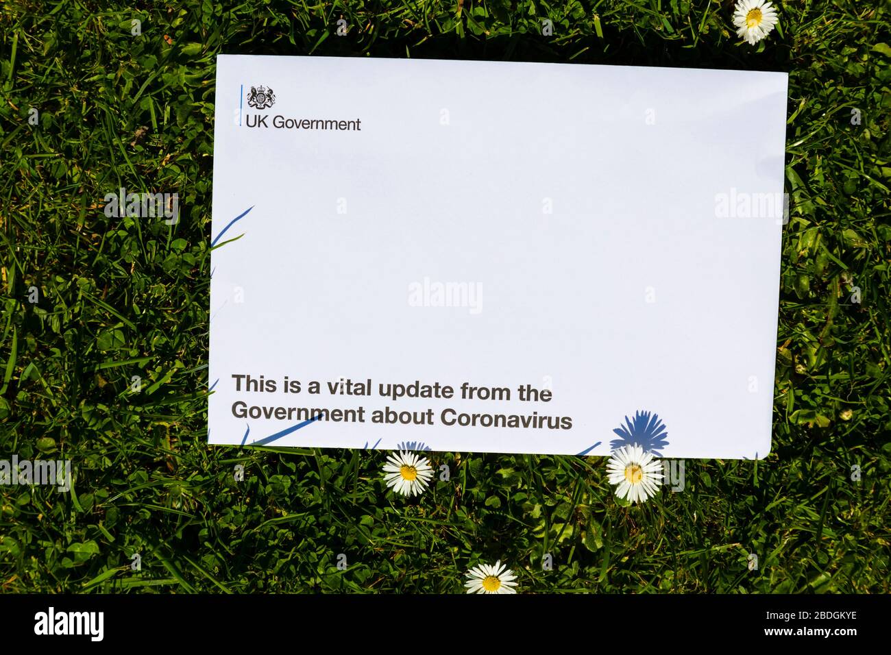 Letter from the British government explaining the need to stay indoors while the Covid-19 Corona virus is pandemic. On grass with daisy flowers. Stock Photo