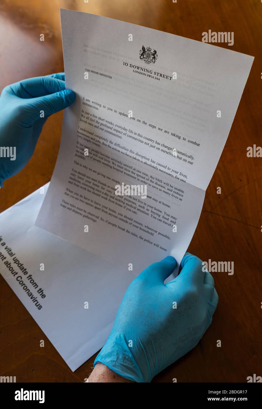 Man wearing surgical gloves holding HM Government letter from Boris Johnson about Covid-19 Coronavirus, United Kingdom Stock Photo