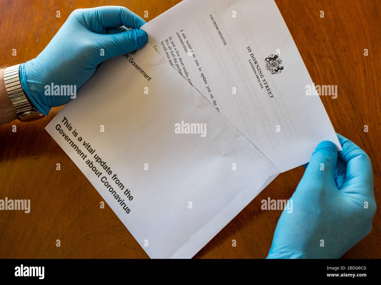 Man wearing surgical gloves holding HM Government letter from Boris Johnson about Covid-19 Coronavirus, United Kingdom Stock Photo