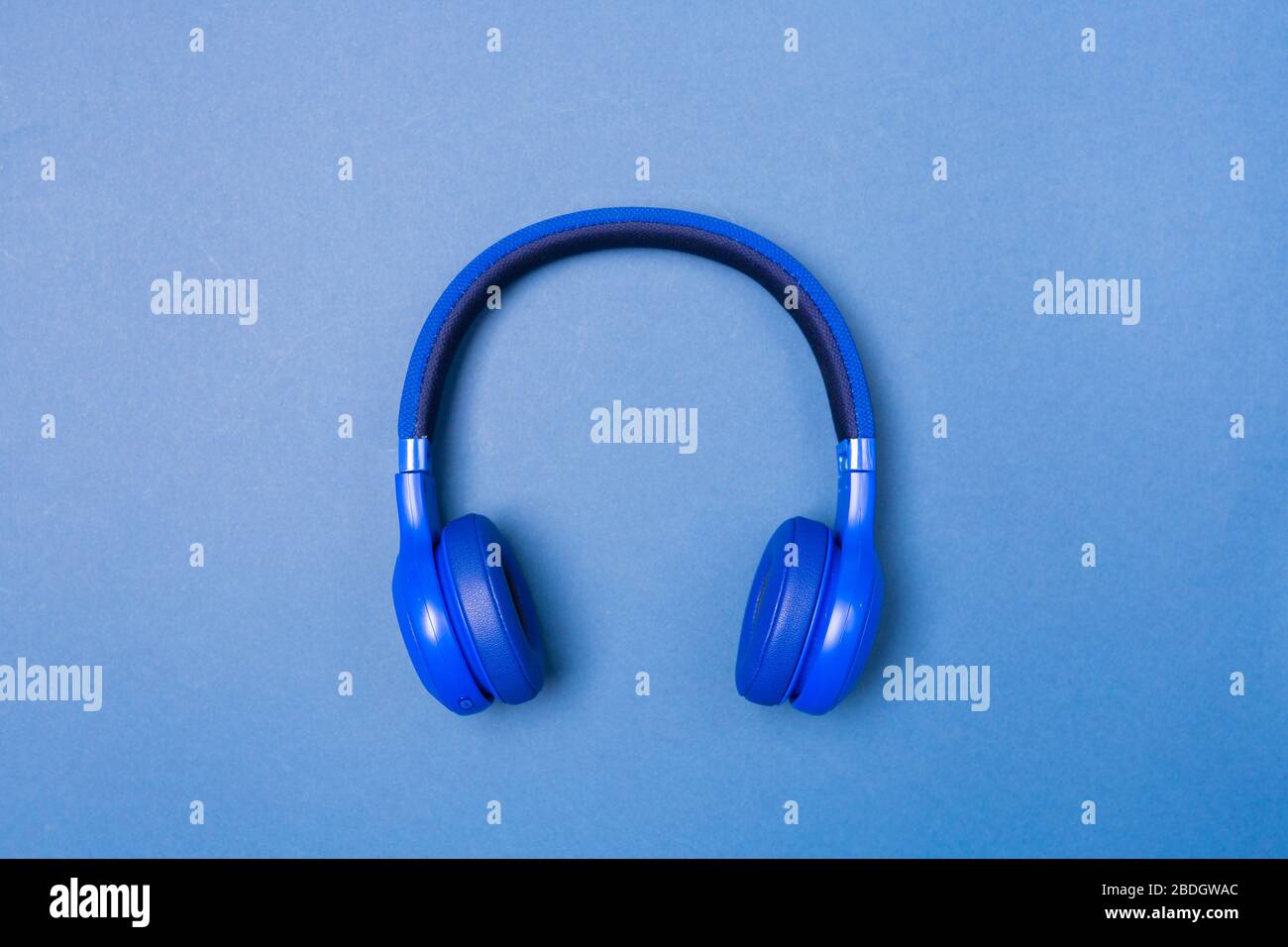 Blue headphones on blue background, top view. Copy space. Space for text.  Stock Photo