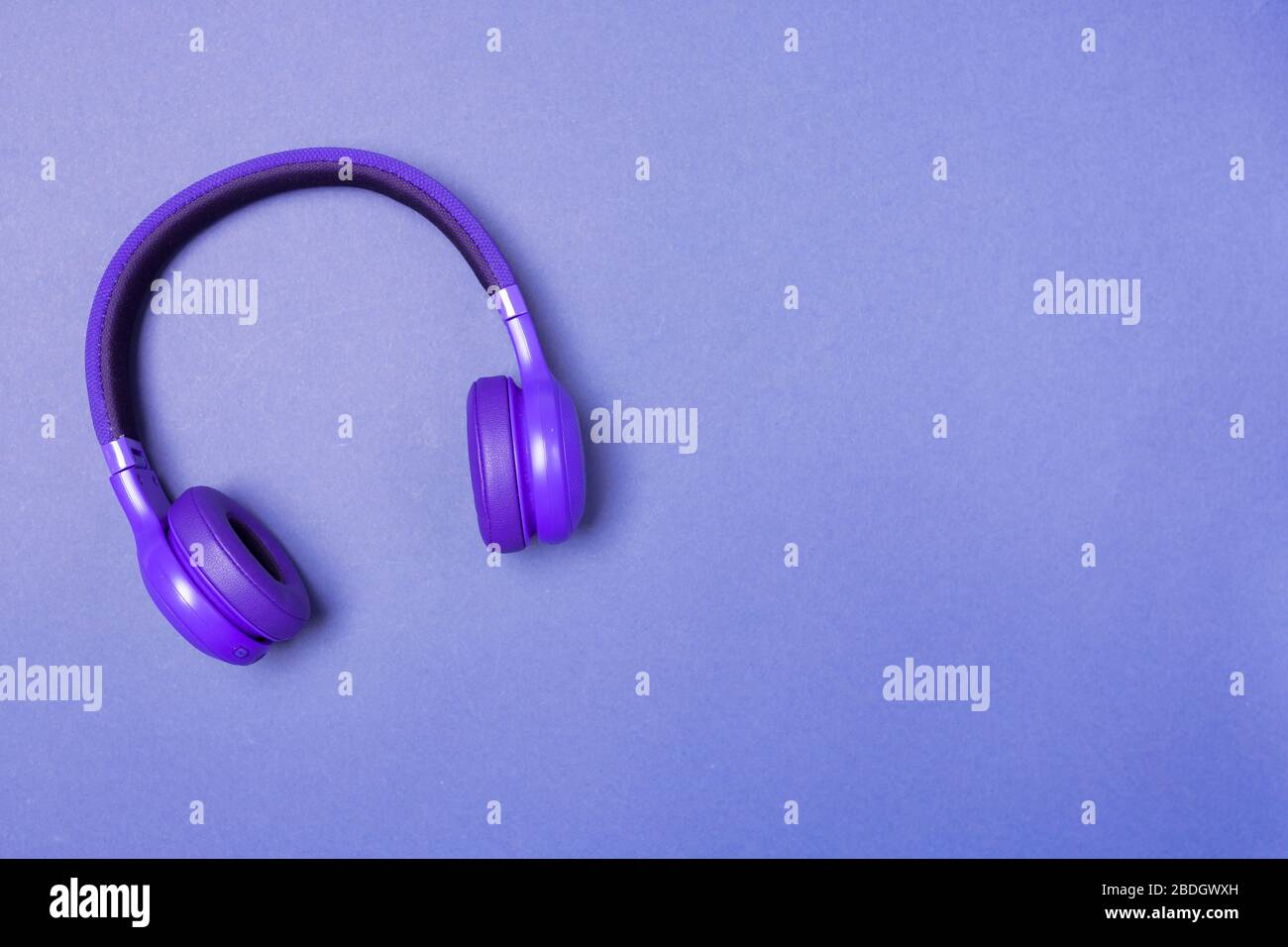 Purple headphones on purple background, top view. Space for text. Stock Photo