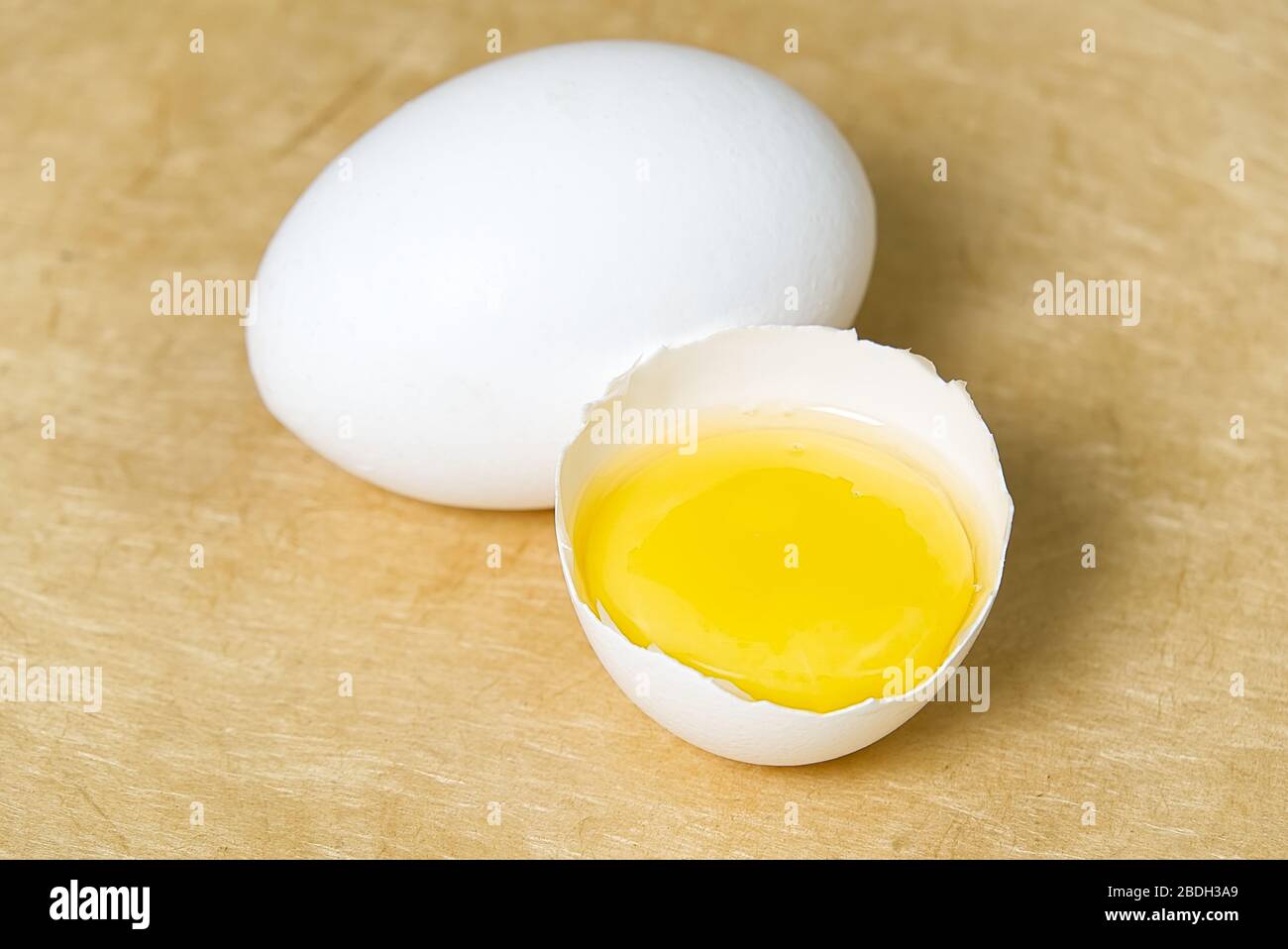 chicken white eggs with half broken egg on beige textured background Stock Photo