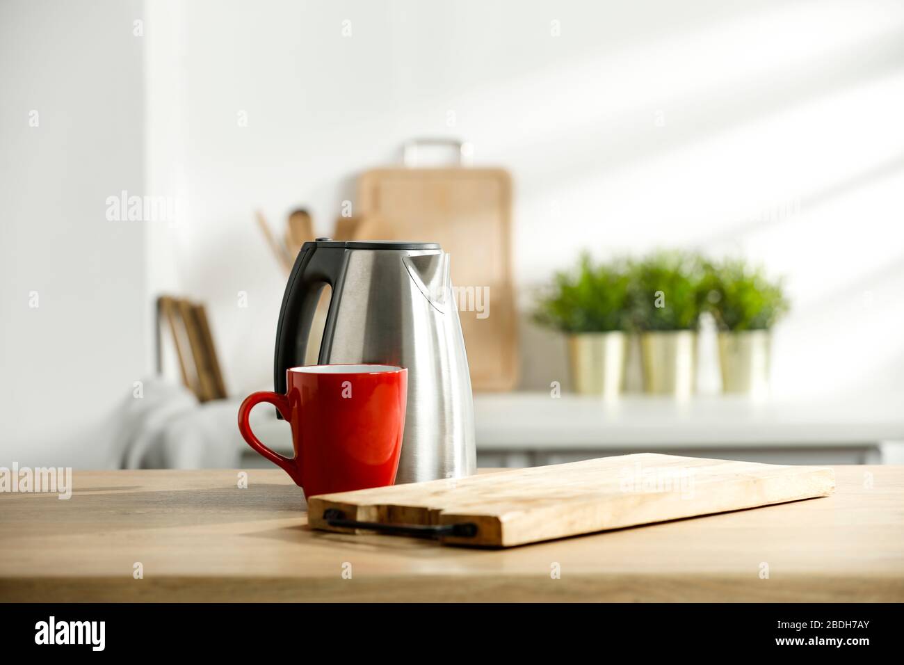 Modern electric kettle and cups of tea on white wooden table in kitchen.  Space for text Stock Photo by ©NewAfrica 317399329