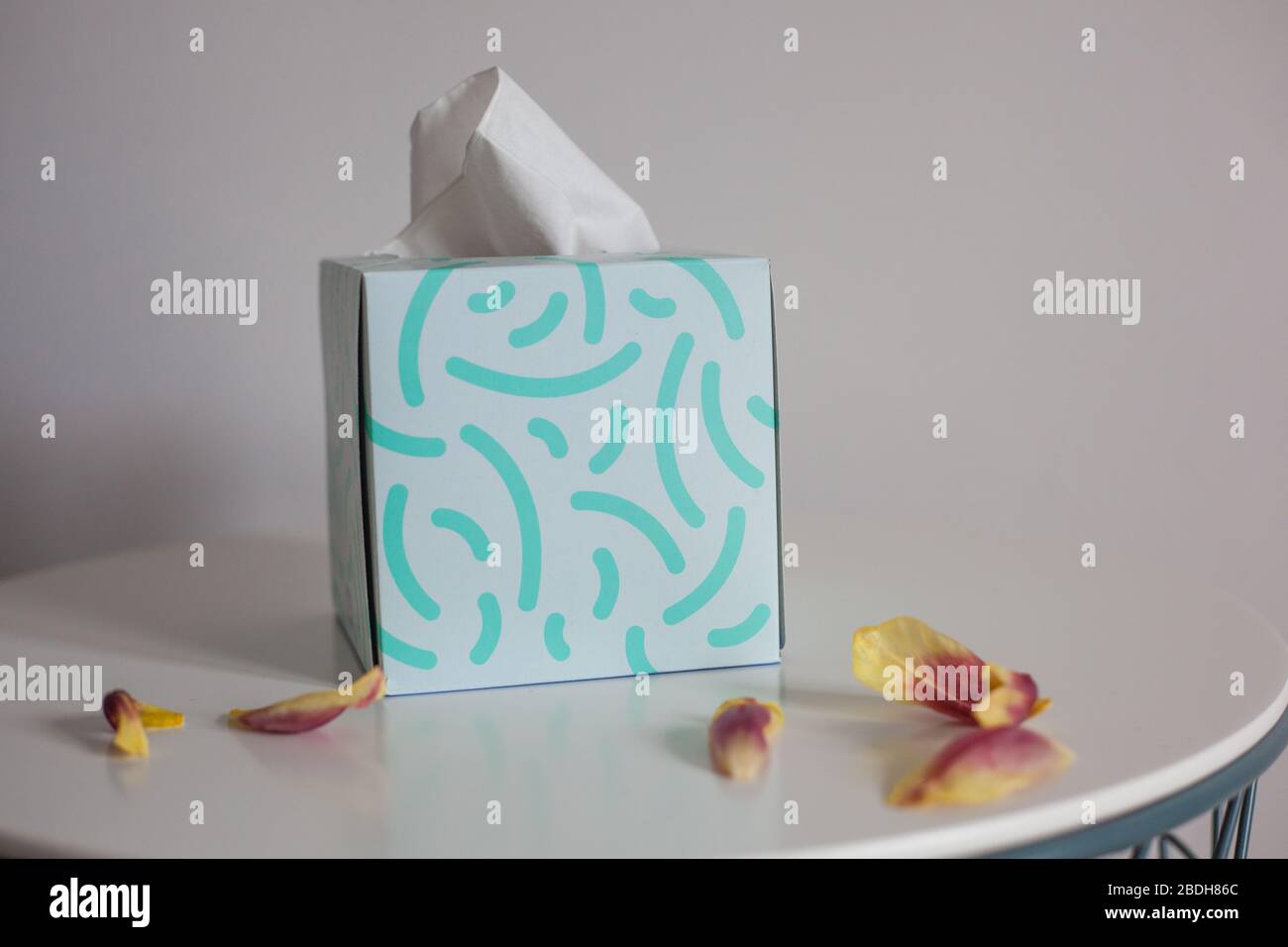 Box of tissues on table with petals Stock Photo