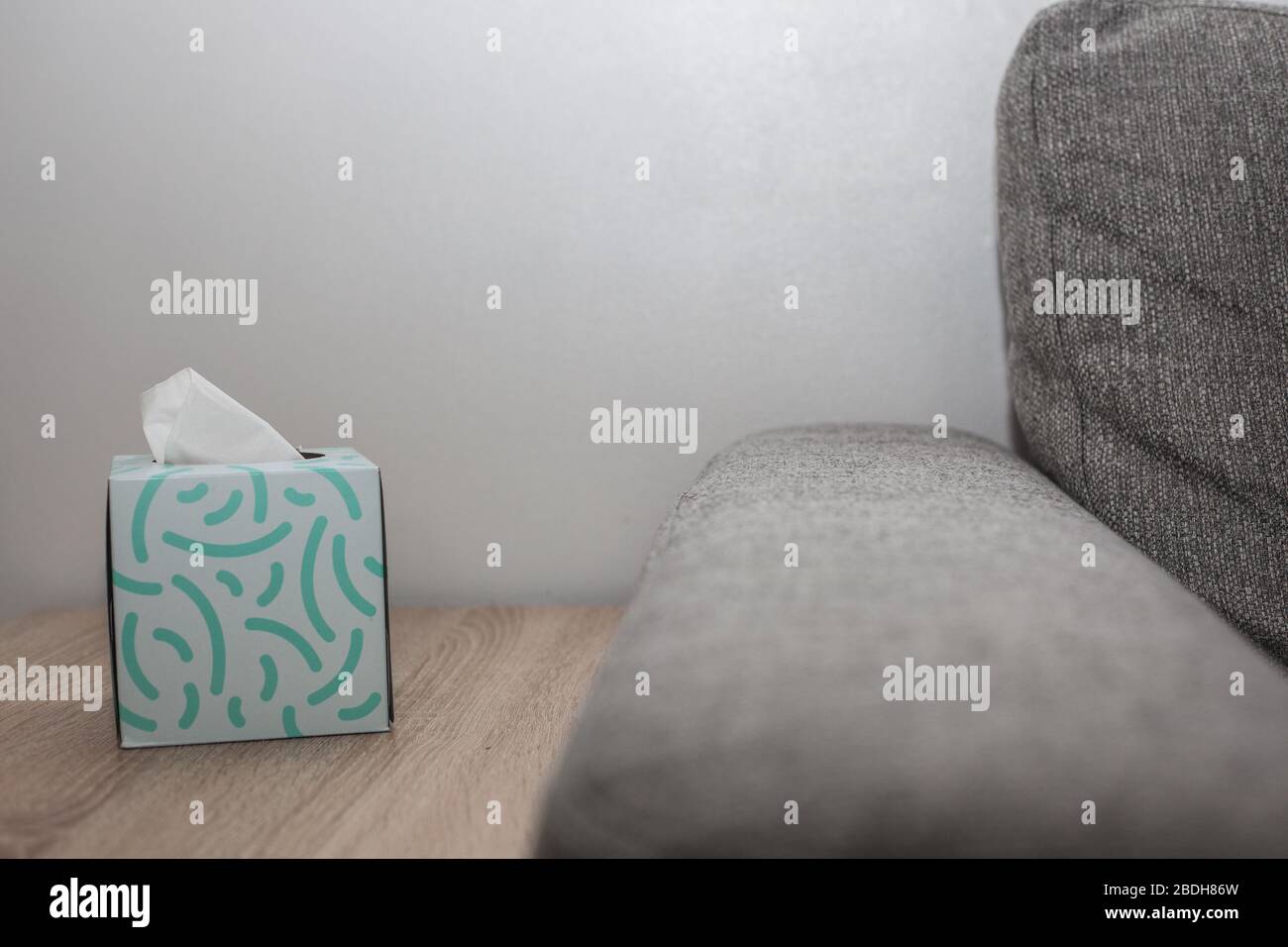 Box of tissues next to grey sofa Stock Photo