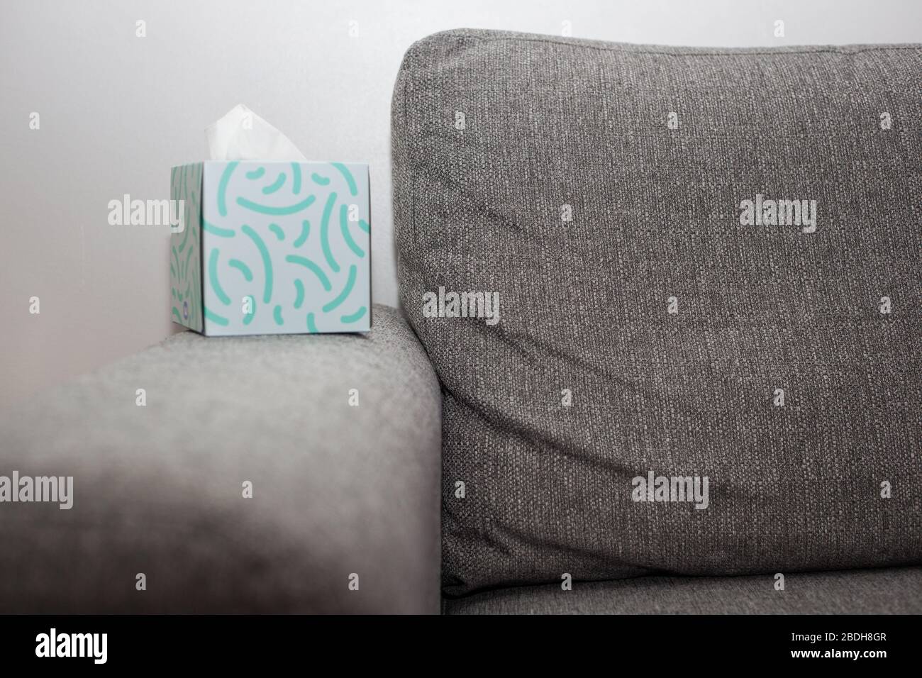 Box of tissues next to grey sofa Stock Photo
