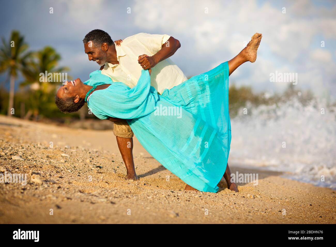 Man dipping his wife, as they dance on beach Stock Photo Alamy