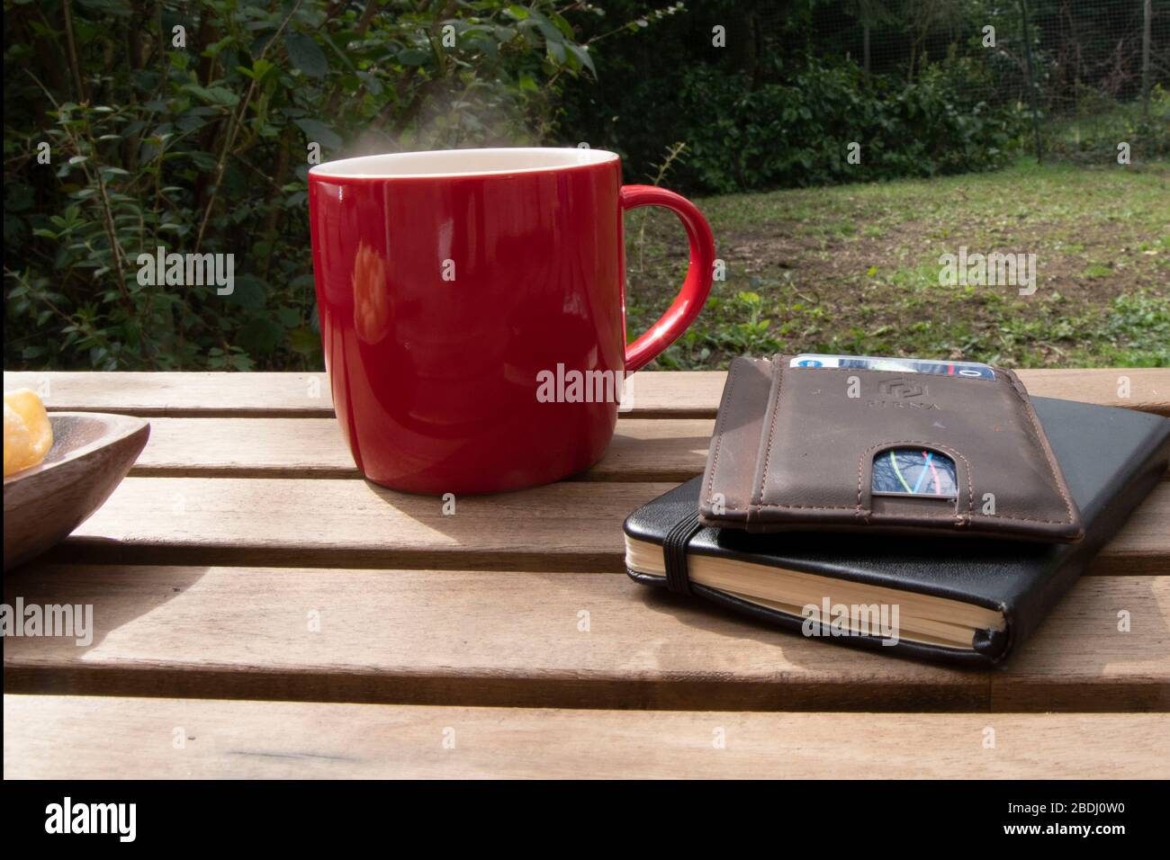 Outside shot of red coffee cup on wooden table, green background Stock Photo