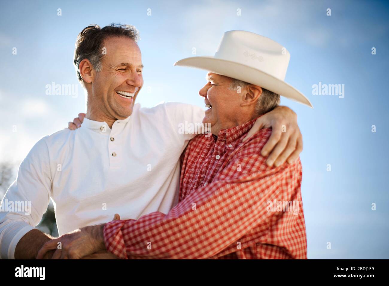 Two mature men embracing and smiling. Stock Photo