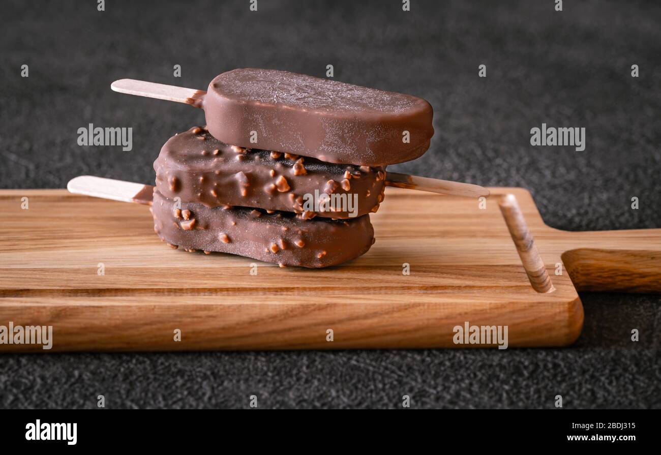 Chocolate-covered vanilla ice cream bars on the wooden board Stock Photo