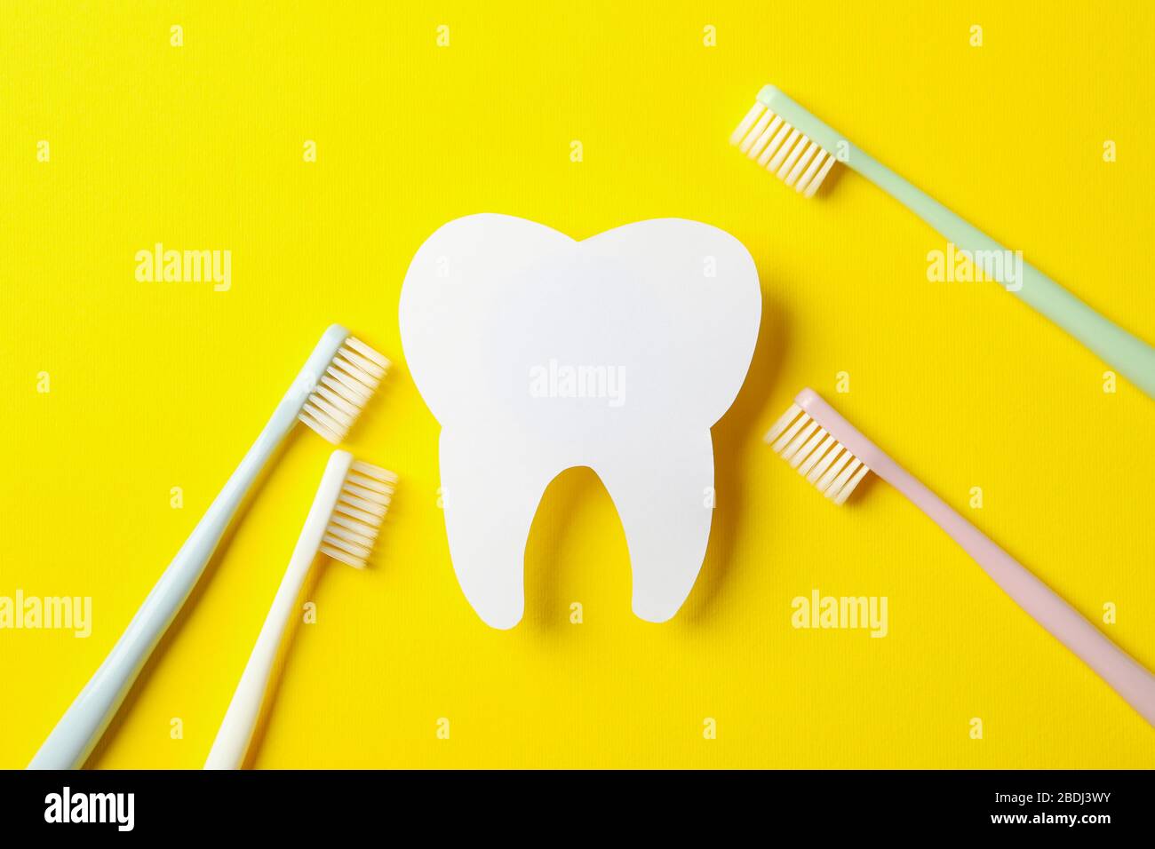 Toothbrushes and tooth on yellow background, top view Stock Photo - Alamy