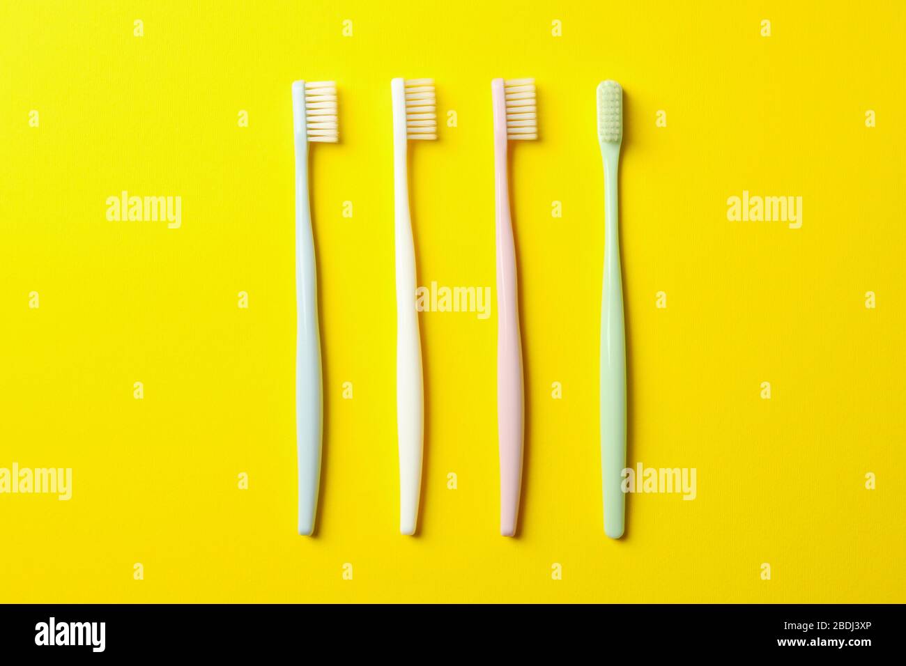 Toothbrushes on yellow background, top view. Dental care Stock Photo ...