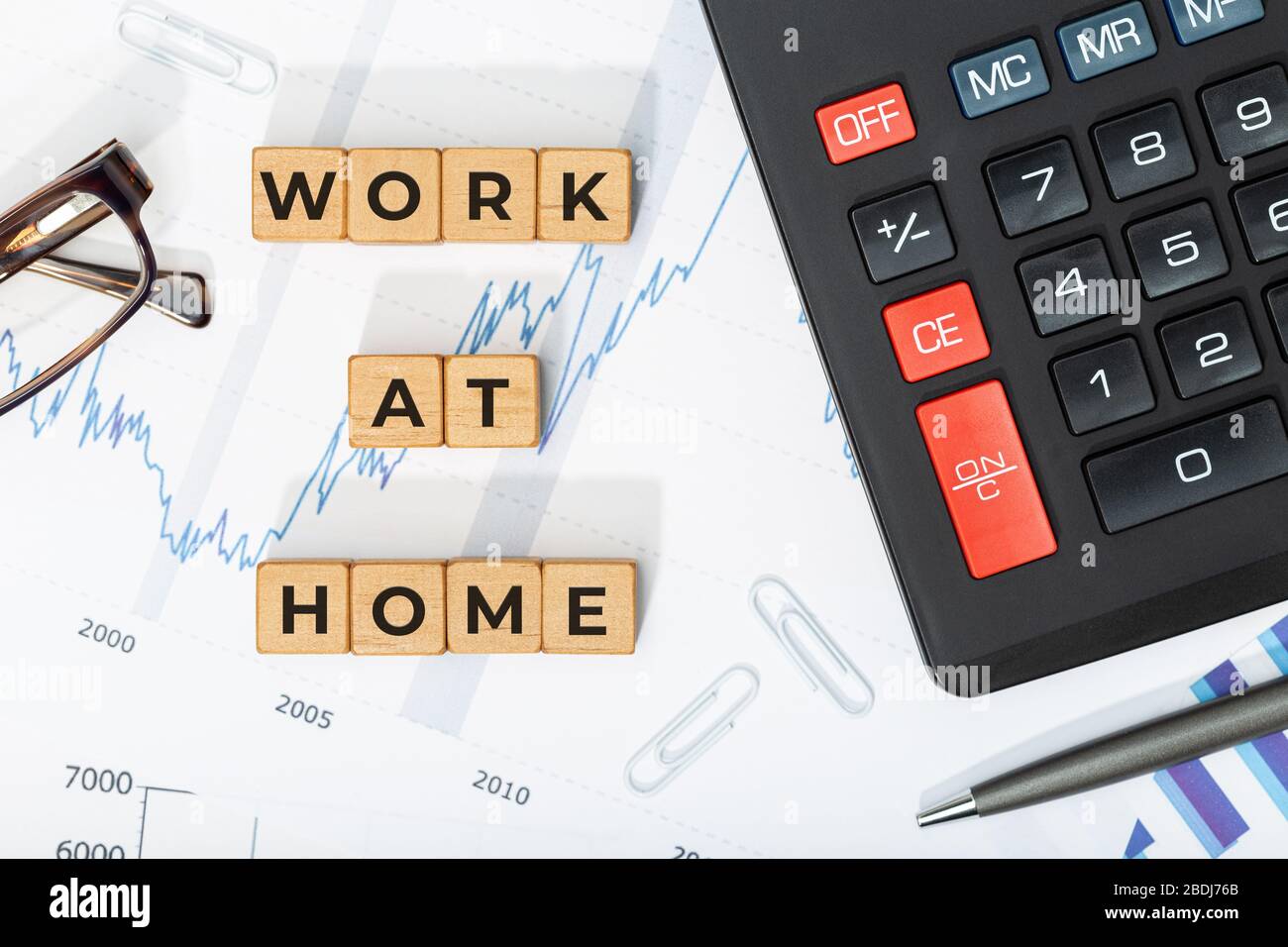 Work at home concept. Wooden blocks with phrase, calculator and printed charts. Business background Stock Photo
