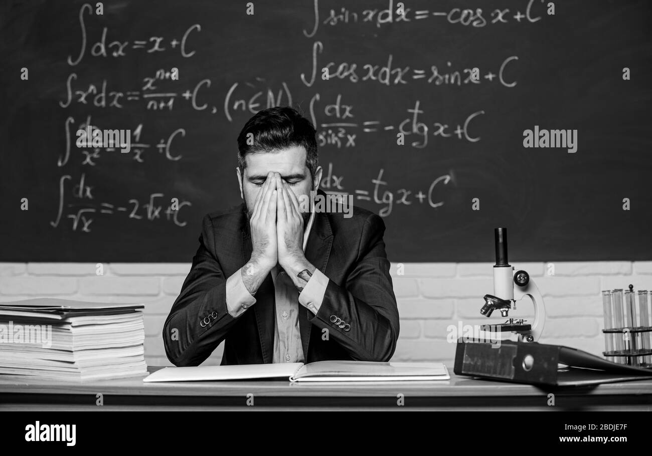 Teaching dumb students. Teacher mature man. Fed up. Man desperate teacher in classroom. No hope for better. Tired and exhausted. Difficult work. Emotional burnout. Teacher give up. Hate his job. Stock Photo