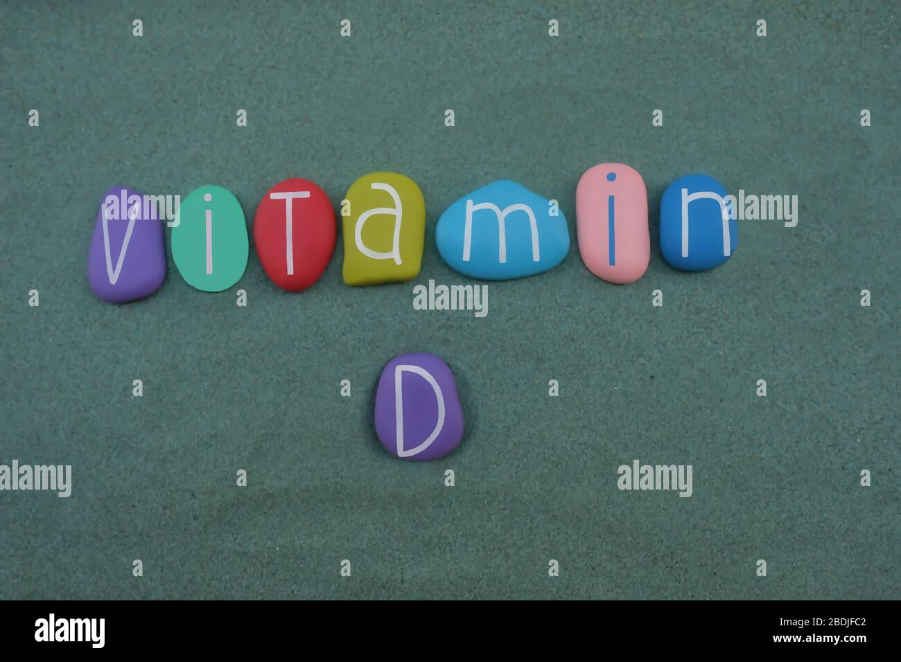 Vitamin D text composed with multi colored stone letters over green