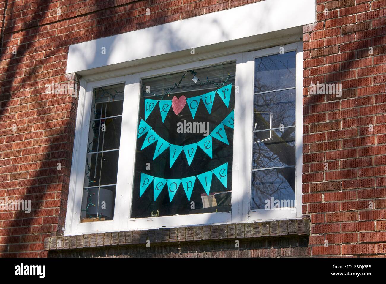 Vancouver, Canada, 07 April 2020. A sign thanking delivery people hangs in the window of an apartment during the COVD-19 pandemic. Stock Photo