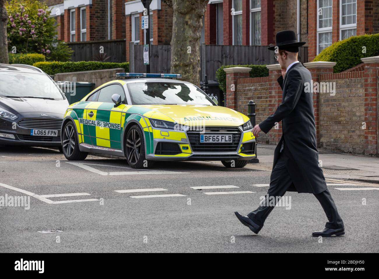 Ultra-Orthodox Jew in the Jewish Community of Stamford Hill passing an ambulance ahead of the Passover celebrations during the COVID-19 lockdown UK Stock Photo
