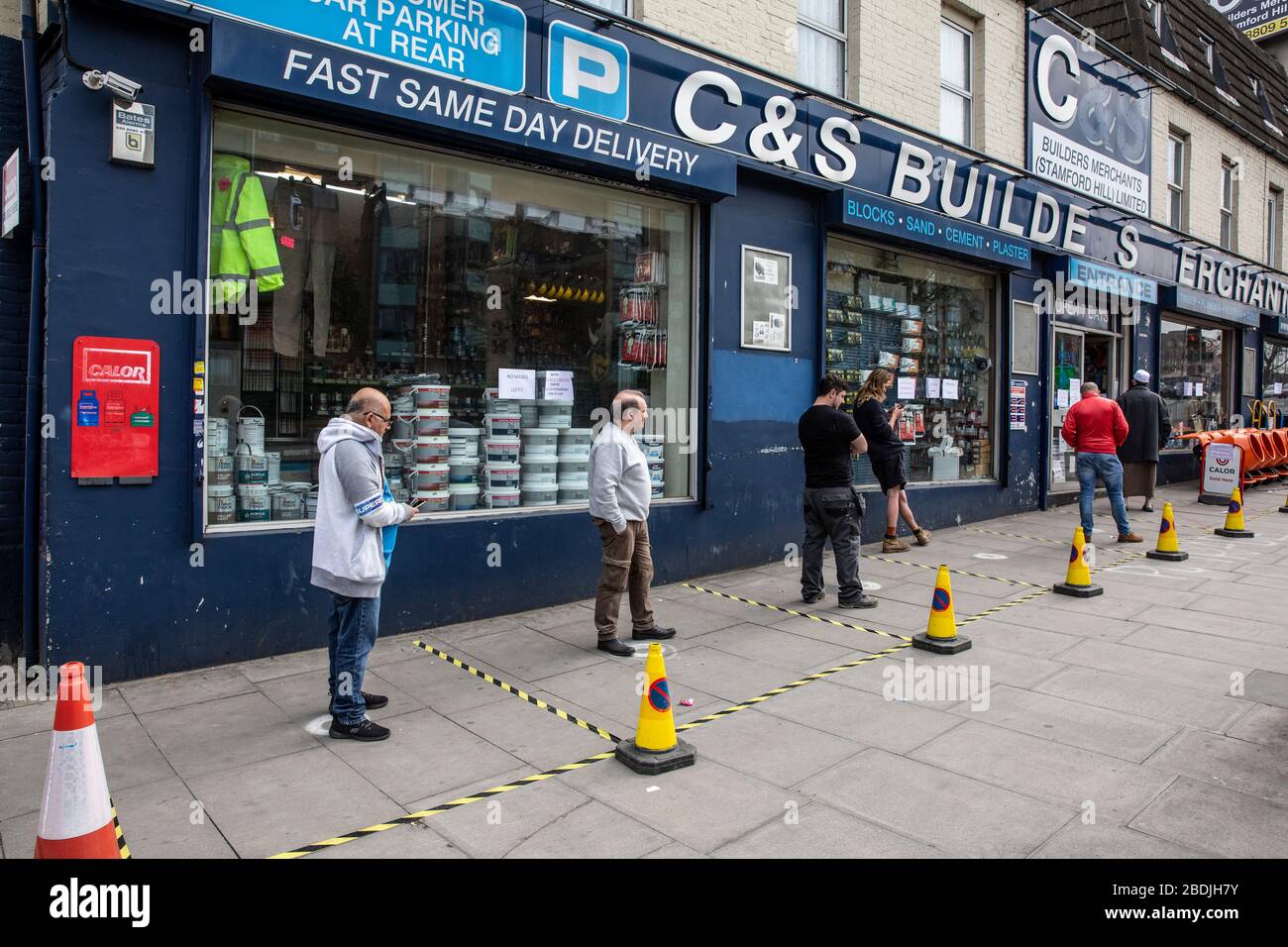 Builders using social-distancing queue outside a Builders Merchants to buy materials during the COVID-19 pandemic lockdown in the capital London, UK Stock Photo