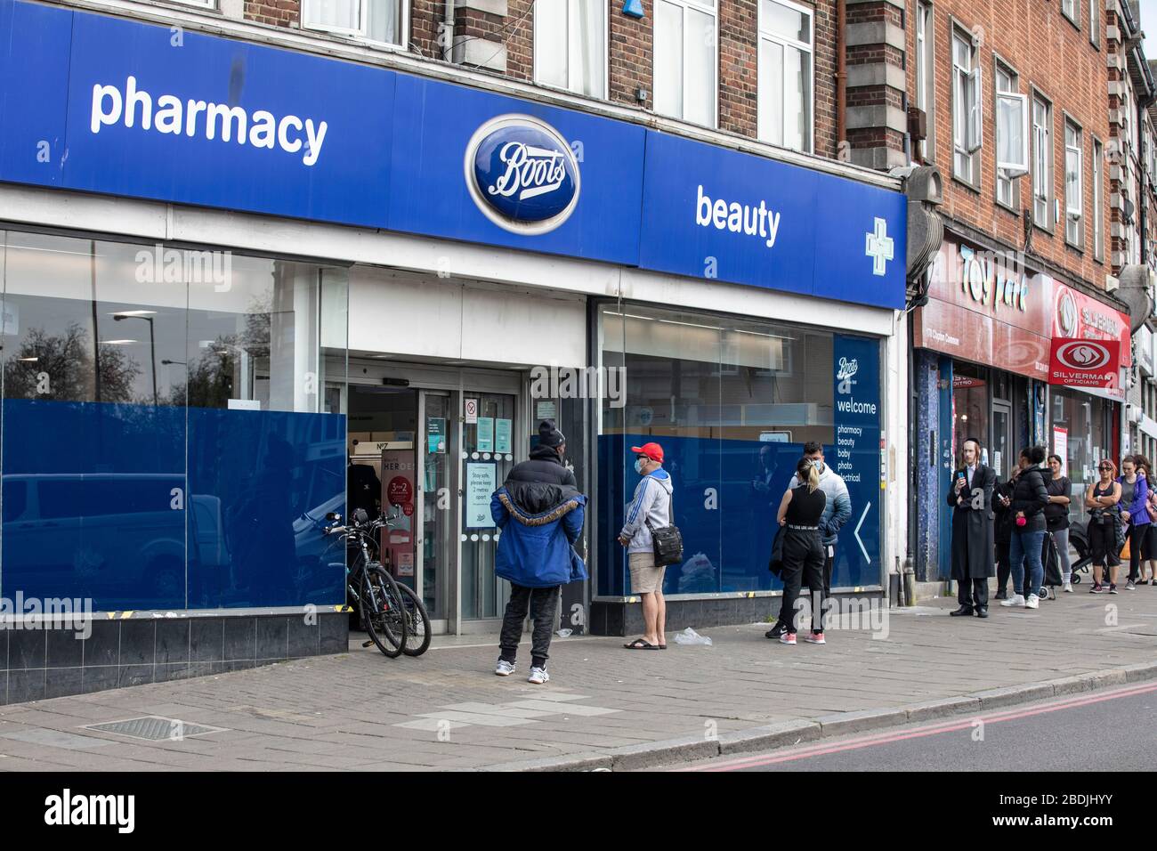 People queue outside a Boots Pharmacy in Stamford Hill, North London, during the COVID-19 lockdown, London, England, UK Stock Photo