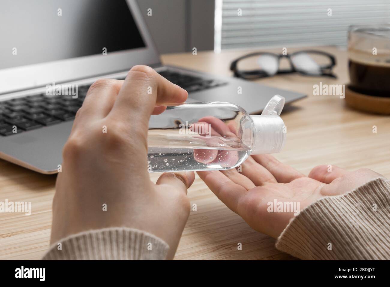 Closeup womans hand uses antibacterial gel to prevent coronavirus on her workplace. Hand sanitizer alcohol gel is pouring from a bottle on a Stock Photo