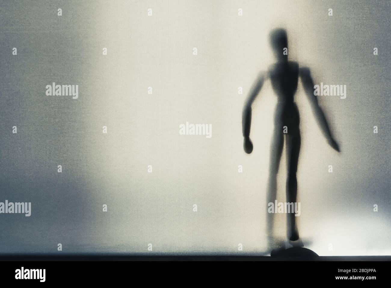 An artist wooden model standing up. Shot through a semi transparent ...