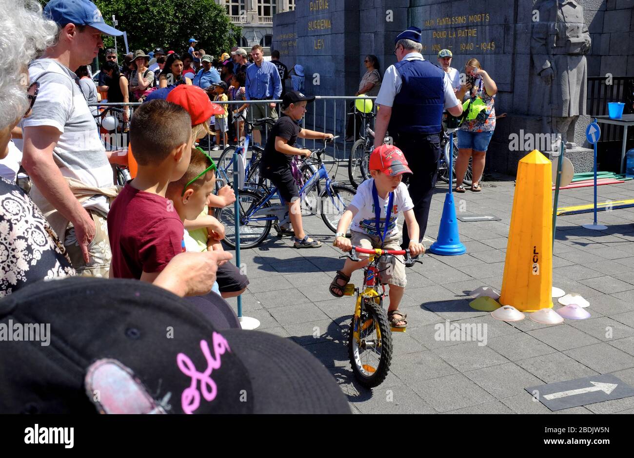children riding bicycle in a traffic rule activity lead by police officer in Police force and Law enforcement show during Belgian National Day celebration. Brussels. Belgium Stock Photo