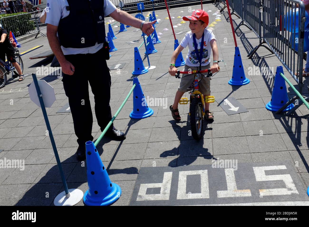A child on children's bicycle in a traffic rule activity lead by police officer in Police force and Law enforcement show during Belgian National Day celebration. Brussels. Belgium Stock Photo